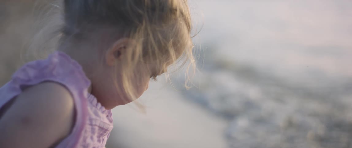 A young girl sits on the beach