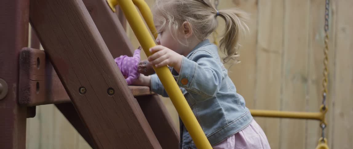The child climbs the ladder in the yard