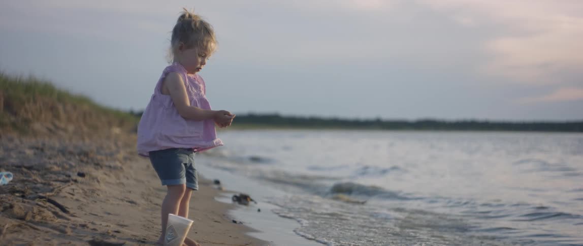 Young girl stands on the beach as the waves roll in