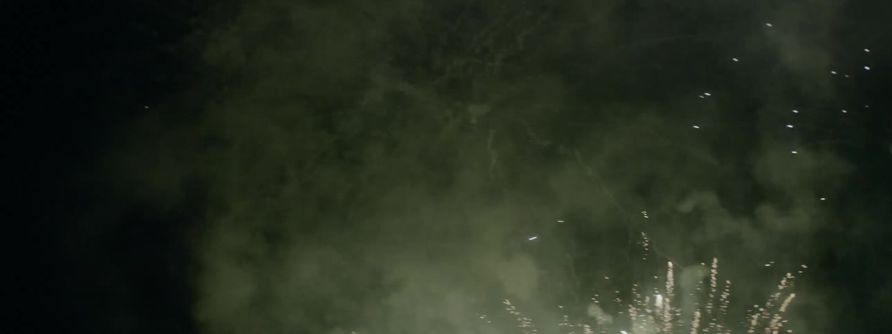 Fireworks explode into a cloud of smoke in the dark sky