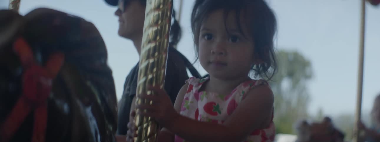 The child smiles as she rides on the merry go round at the carnival