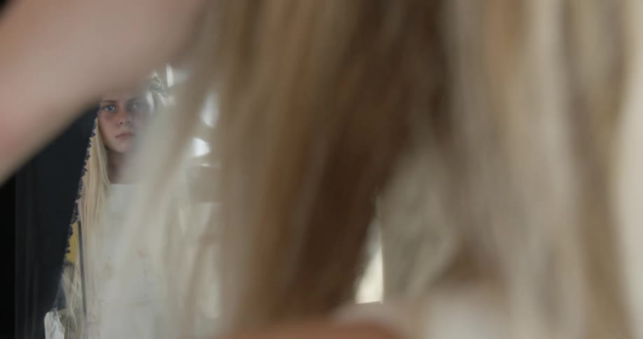 A girl brushes her hair in the mirror