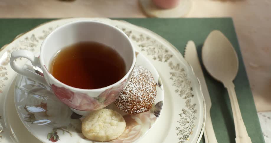 A cup of tea with some pastries on a small plate