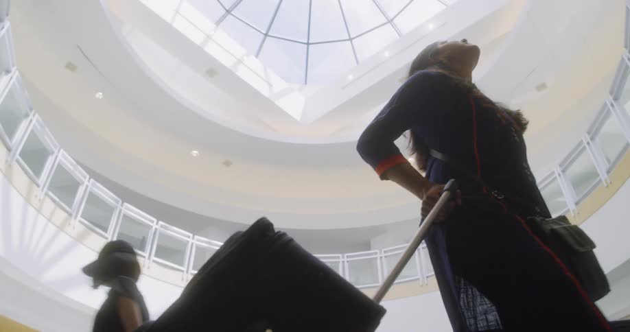 A woman pulls a suitcase inside a building with a domed ceiling