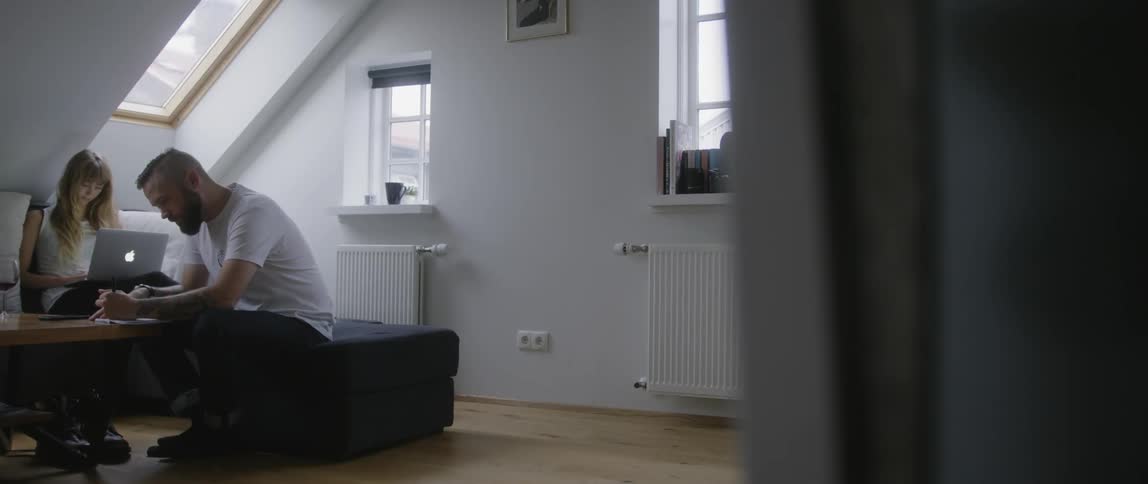 A man sits on a couch in a room with sloped ceilings