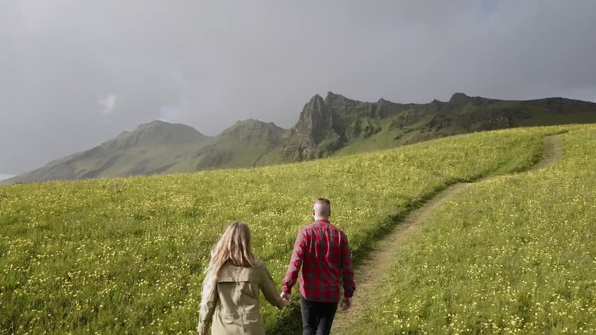 The two people hold hands walking up the hill