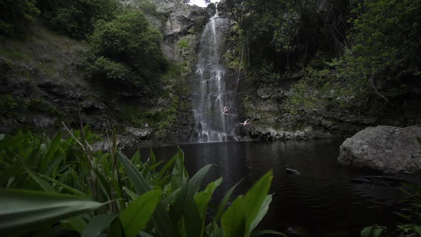 The man swings high falling into the water near the waterfall