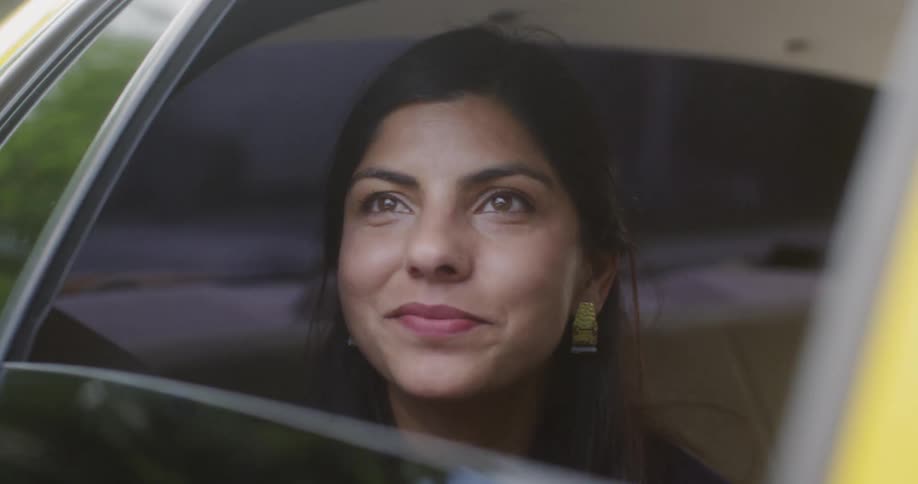 A woman smiles while riding in the backseat of a car