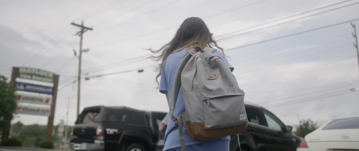 The woman carries her backpack to the vehicle