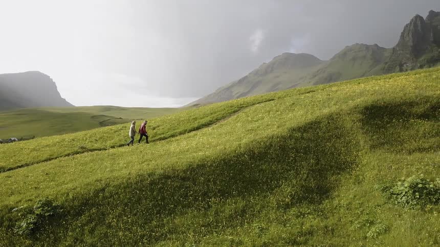 A couple hiking up a grassy mountain