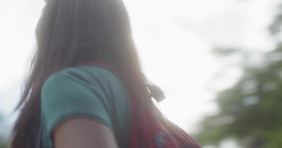 A woman smiles and approaches a building on a college campus