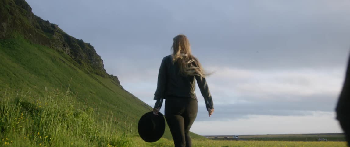 A man and woman run in a grassy rural field