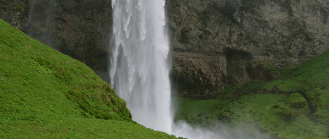 A waterfall flows over a rocky cliff