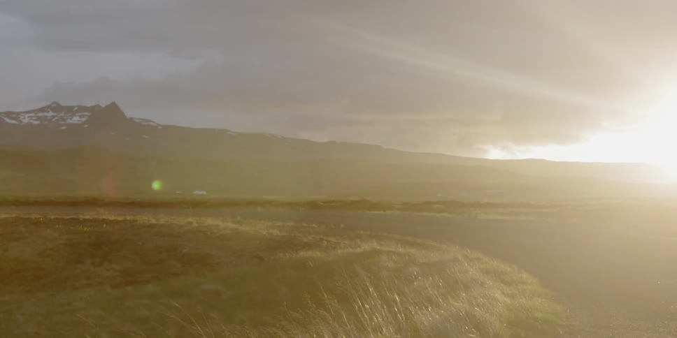 Sunlight is streaming across a road in a natural setting on a cloudy day