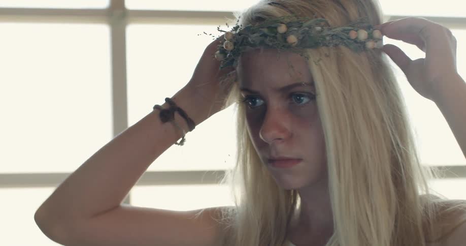 A woman is adjusting her crown of flowers