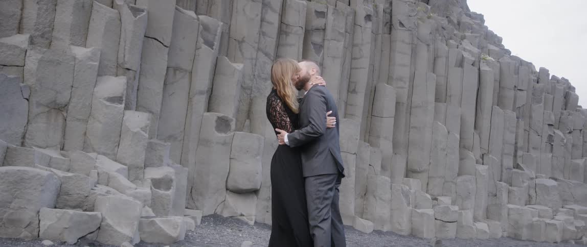 The man and women kiss in front of the rocks