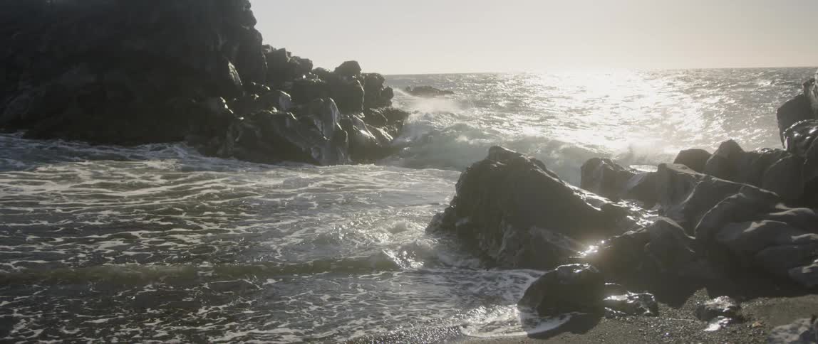 The waves crash against the shore on a cloudy day