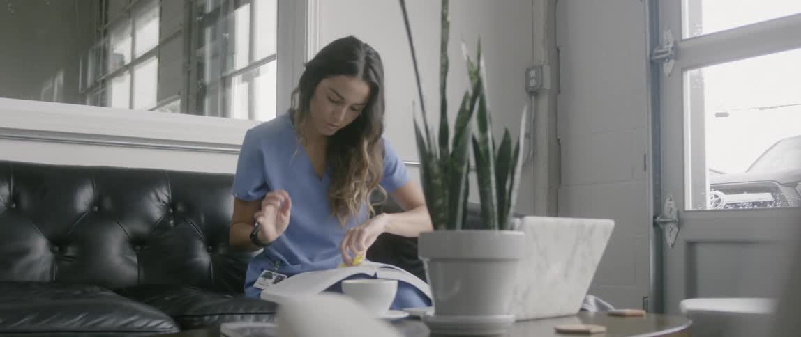 The woman sits on the couch highlighting a book