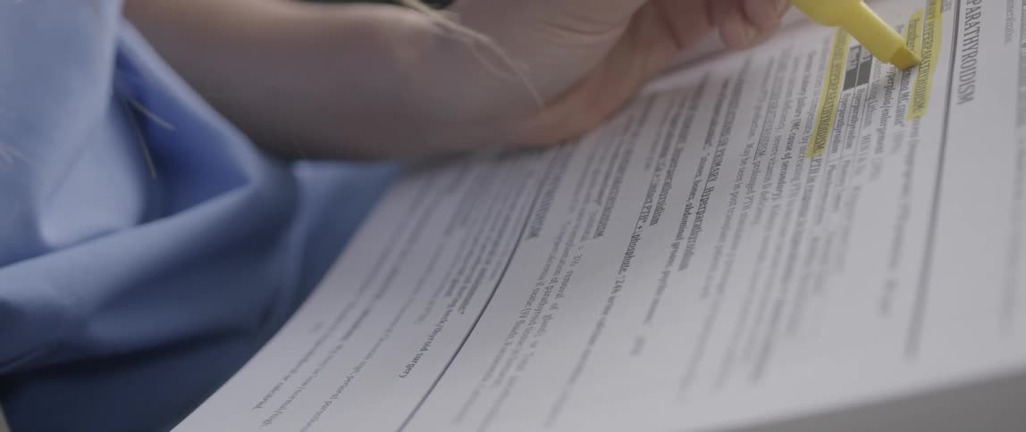 A woman's hand rests on the page of a book she is holding