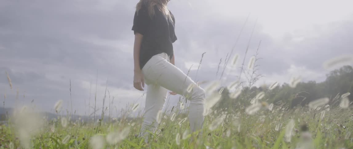 A woman walks in a meadow on a cloudy day