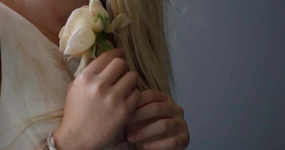 A woman in a stained white dress holds a wilting rose