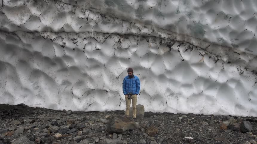 A man stands in front of a large ice wall