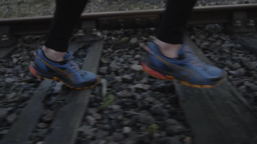 The person is jogging over the train tracks