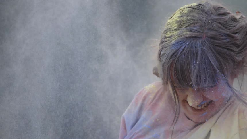 The woman smiles as she is covered with colored dirt