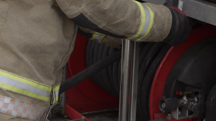 The firefighter winds up the hose