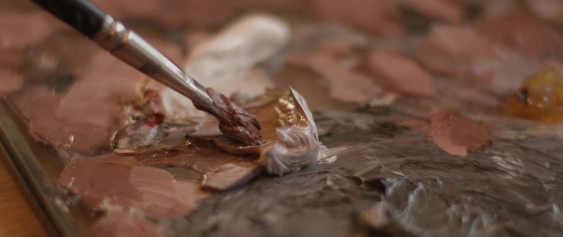 The person gets paint with the brush