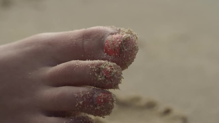 Sand sits on the end of a woman's toes