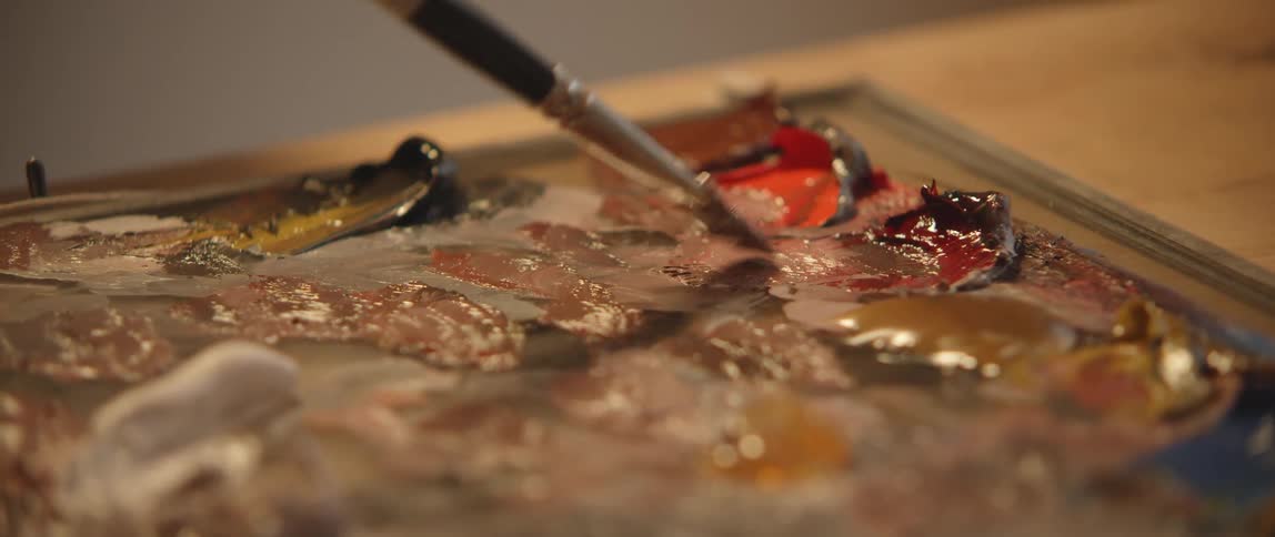 An artist mixes paint colors together