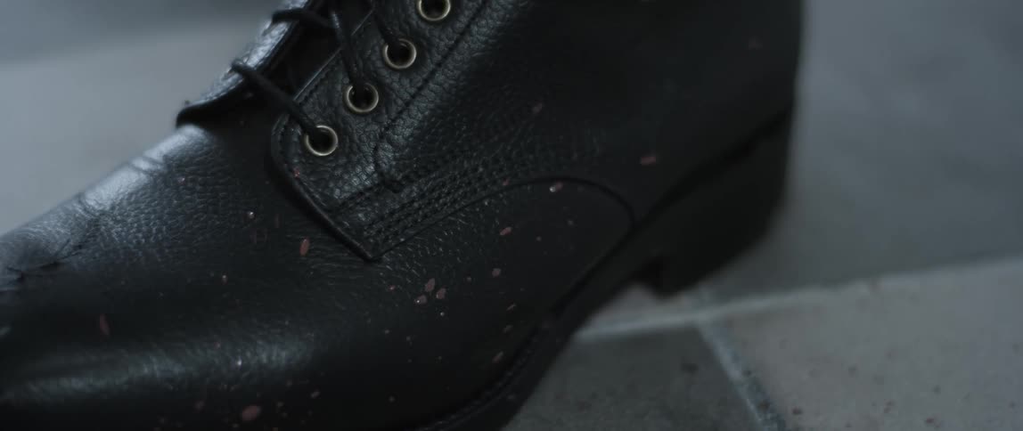 Spots of mud on a black boot with black laces