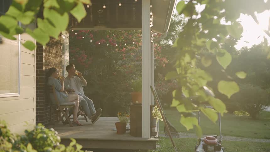 The two people have drinks on the porch together