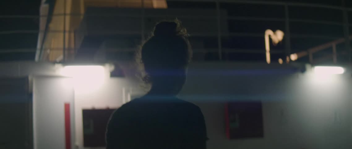 The woman walks on the boat outside at night