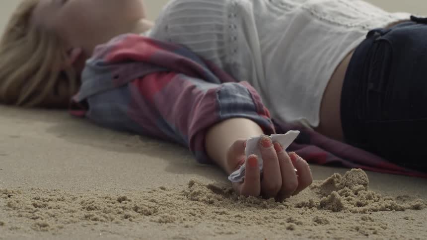 The woman is sleeping in the sand