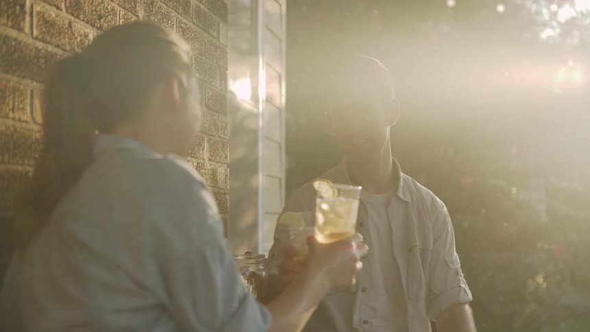 Man and woman sit down at a table and drink beverages on a sunny day