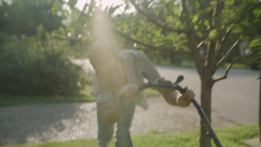 A man mows a lawn on a sunny day