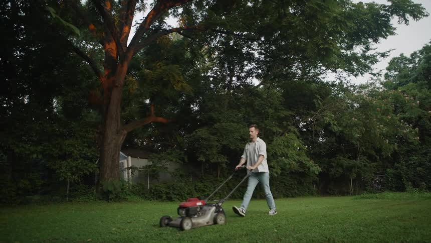 Man pushes a lawnmower over a large yard