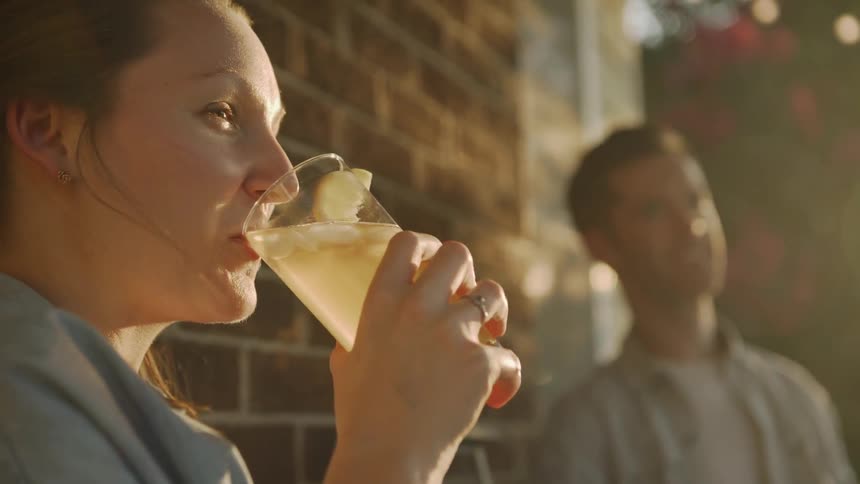 The woman takes a drink on a sunny day