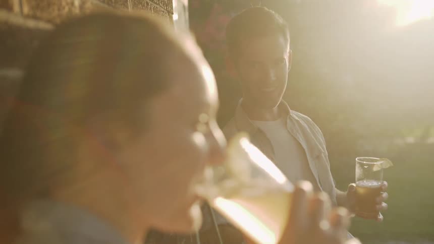 Man and woman sit on a porch drinking iced tea