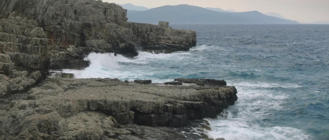 Water splashes up on rocks at sunset
