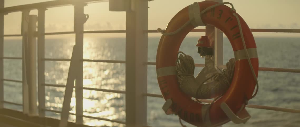The life preserver hangs on the railing of the moving ship