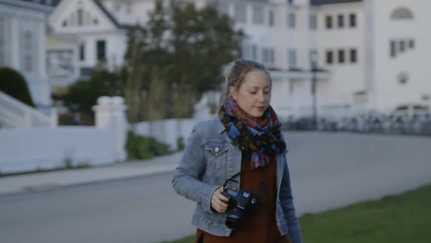 The woman walks with her camera and takes a photo