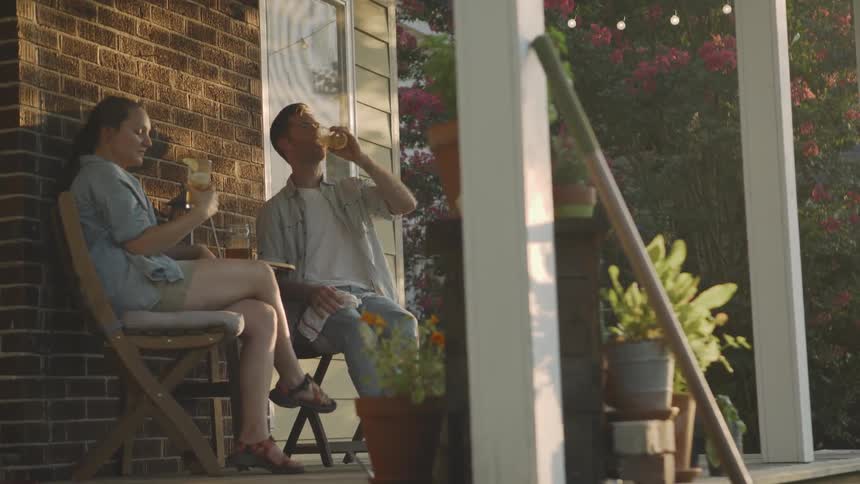 A man and woman toast a drink on the porch
