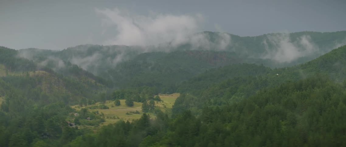 Clouds float above mountains covered in trees
