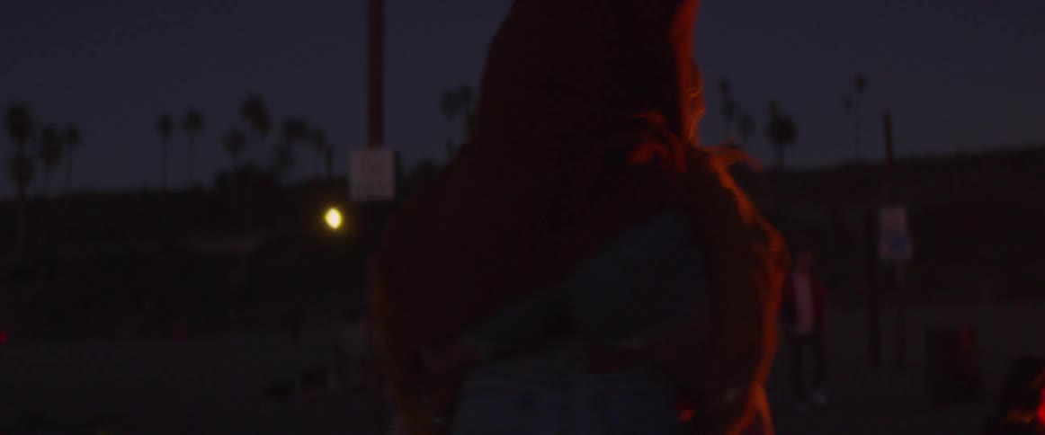A woman rides on a friend's back next to a bonfire