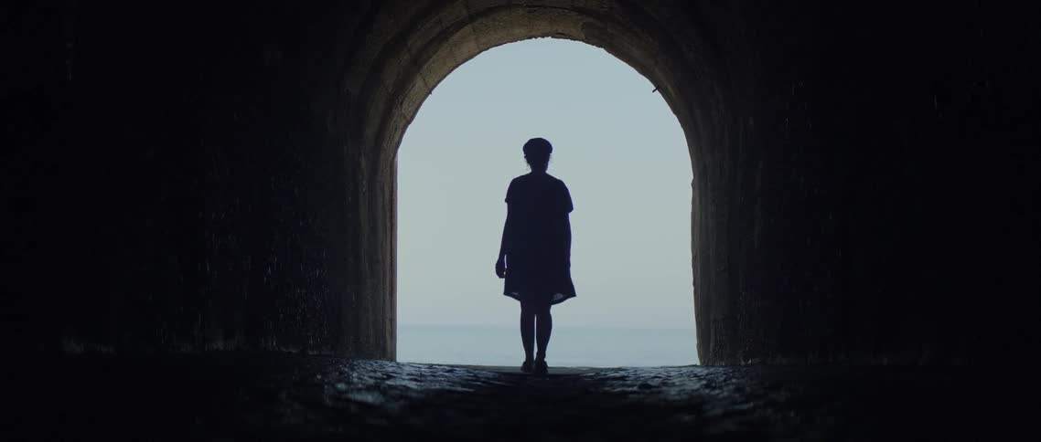The person walks out of the tunnel
