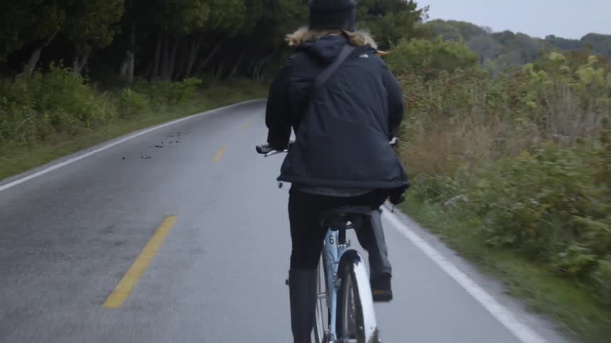 Woman rides a bike on a country road