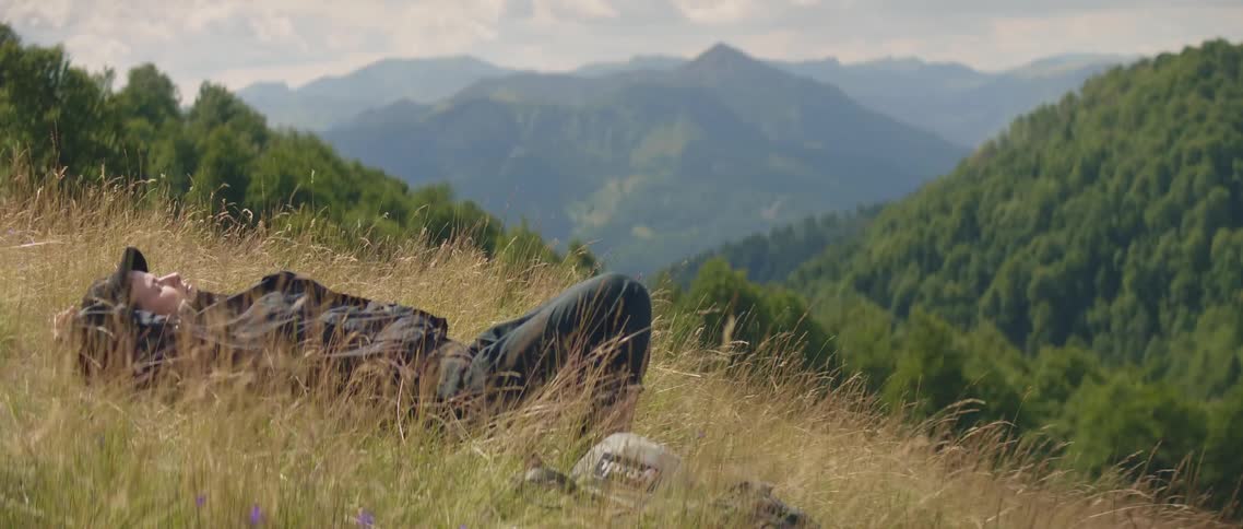 Woman lays on her back in the weeds on a windy day
